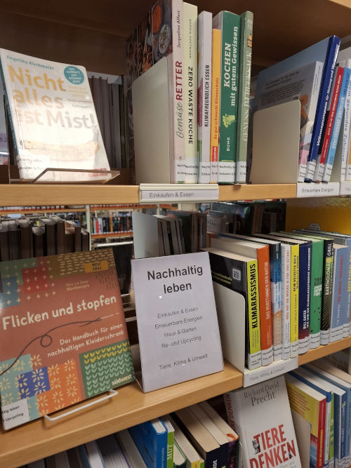 Abtielung »Nachhaltig Leben« in der Eichenauer Gemeindebücherei Zu sehen ist ein Regal, auf dem verschiedene Bücher mit Titeln wie »Nicht alles ist Mist!« oder »Flicken und stopfen« stehen.